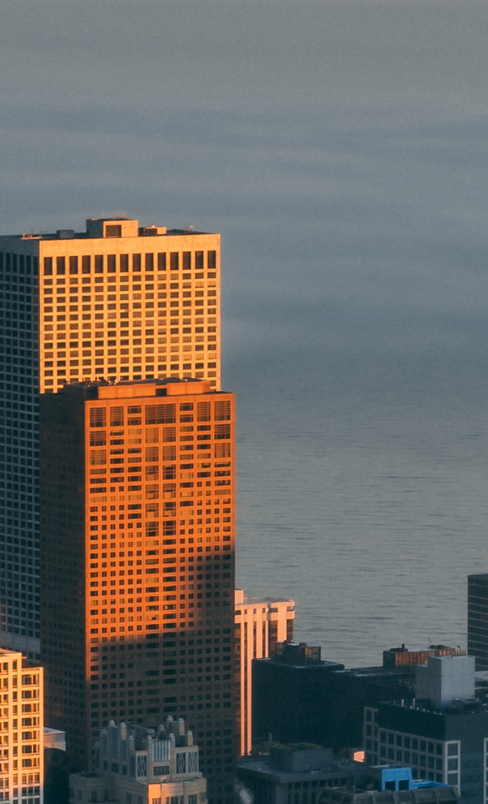 Skyscrapers over a calm ocean at sunset